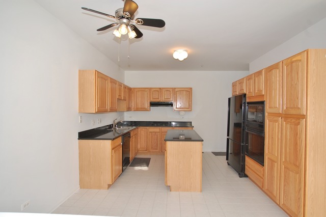 2103 Ivy Ridge Drive Hoffman Estates, IL 60192 - Photo 7 of 24 a kitchen with stainless steel appliances a stove a refrigerator a sink a microwave oven with a dining table and chairs