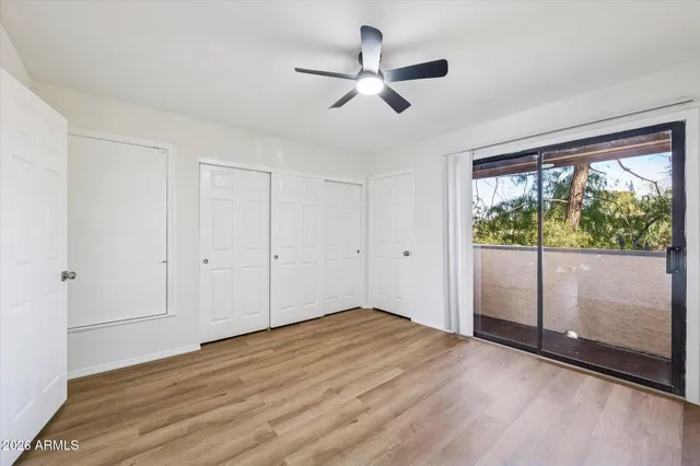 an empty room with wooden floor and a ceiling fan