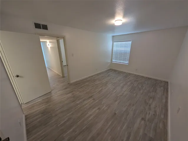 an empty room with wooden floor and mirror