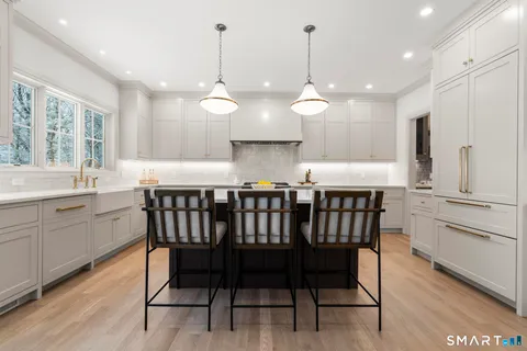 a large kitchen with a large counter top a sink a window and stainless steel appliances