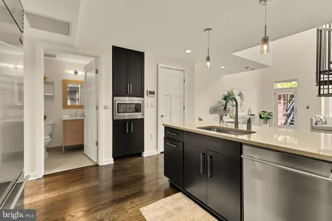 a kitchen with stainless steel appliances granite countertop a refrigerator a sink dishwasher and a oven with wooden floor