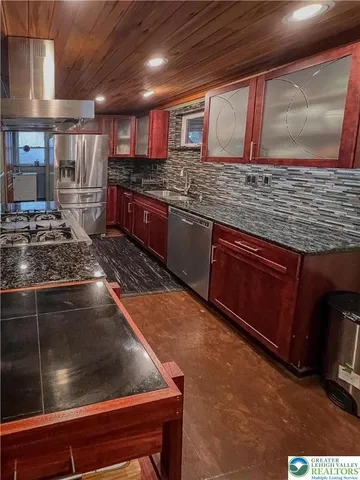 a kitchen with stainless steel appliances granite countertop a stove a sink and a microwave