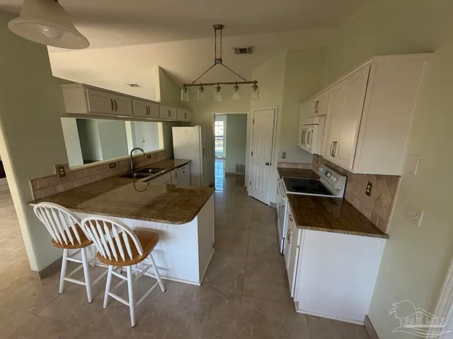 a kitchen with stainless steel appliances kitchen island granite countertop a table chairs and a refrigerator