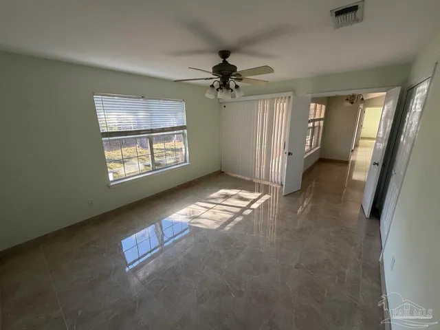 an empty room with windows and fan