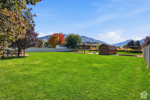 1447 Meadow Lane Mapleton, UT 84664 - Photo 48 of 67 Expansive grassy yard with a white privacy fence, wood-finish shed, and a structured pergola