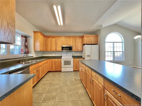 a large kitchen with stainless steel appliances granite countertop a sink counter space cabinets and a large window