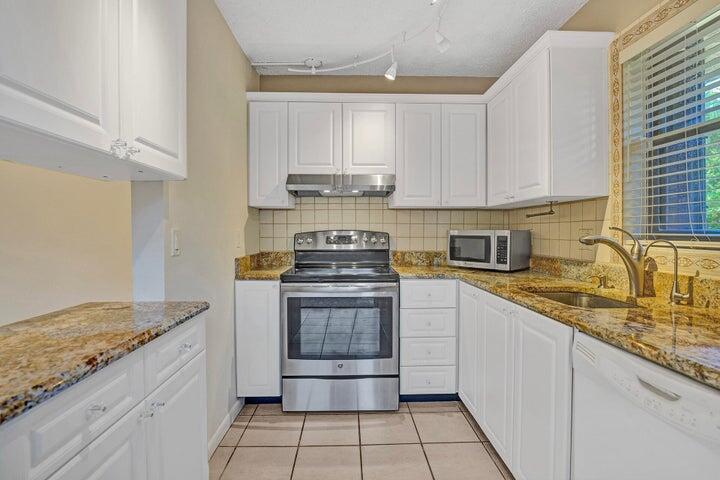3134 Southwest 20th Terrace, Unit 11D Delray Beach, FL 33445 - Photo 2 of 14 a kitchen with stainless steel appliances granite countertop a stove sink and cabinets