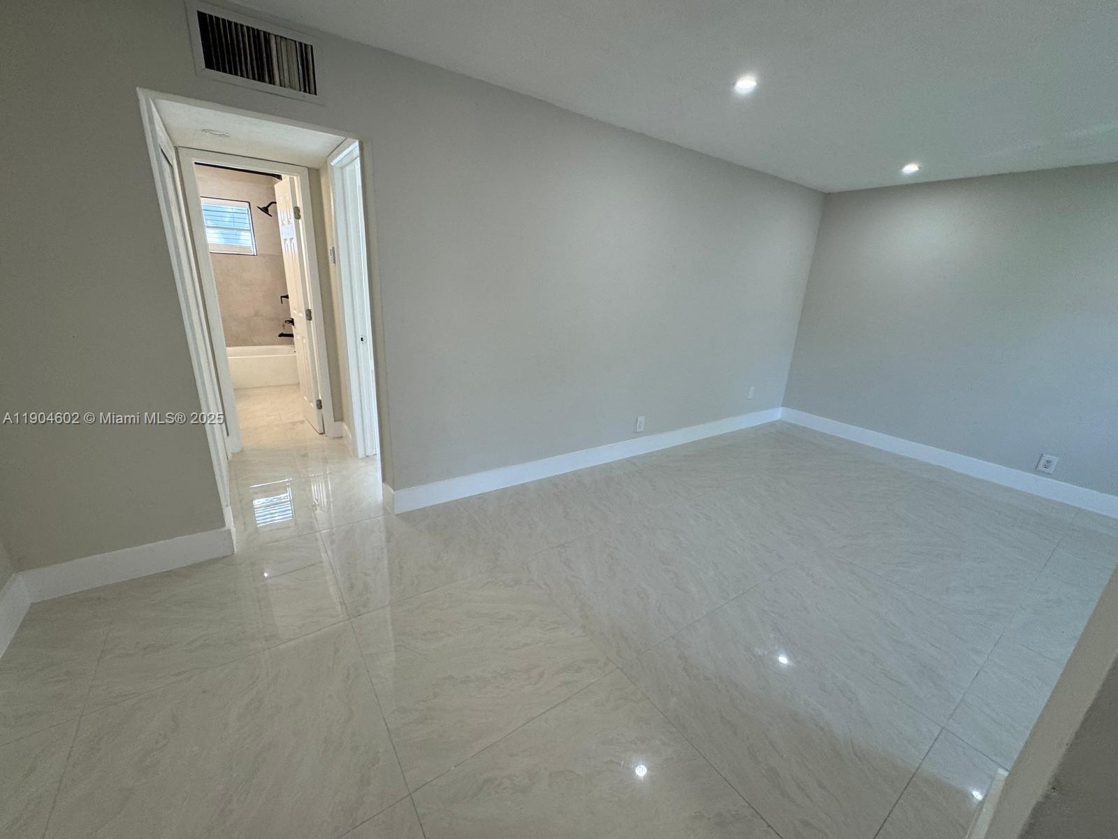 2418 Polk Street, Unit 104 Hollywood, FL 33020 - Photo 11 of 16 an empty room with wooden floor and a window