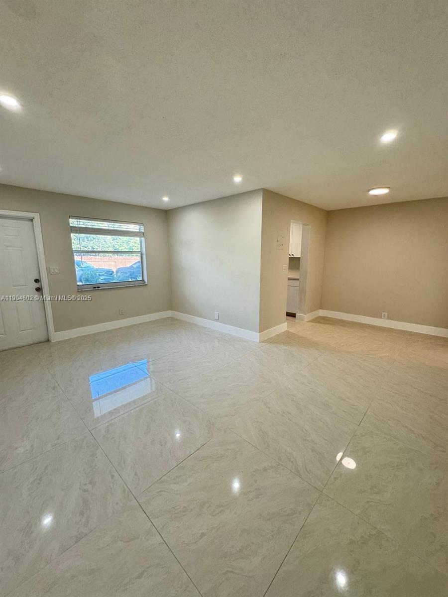 2418 Polk Street, Unit 104 Hollywood, FL 33020 - Photo 13 of 16 an empty room with windows and ceiling fan