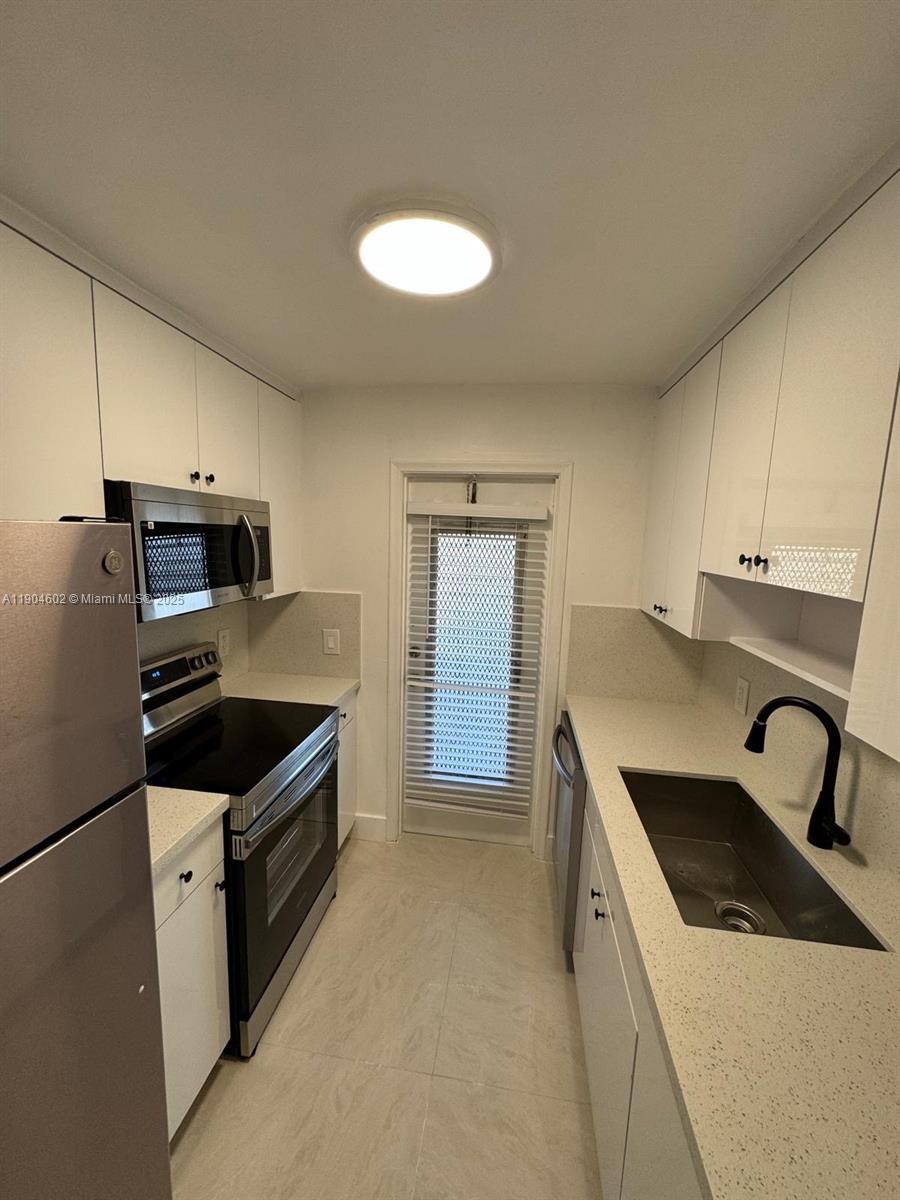 2418 Polk Street, Unit 104 Hollywood, FL 33020 - Photo 2 of 16 a kitchen with granite countertop a stove and a sink