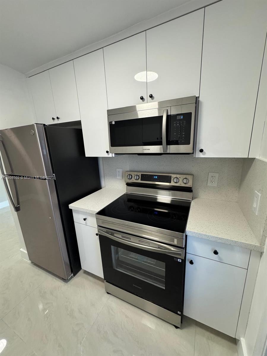 2418 Polk Street, Unit 104 Hollywood, FL 33020 - Photo 4 of 16 a kitchen with stainless steel appliances a stove microwave and refrigerator