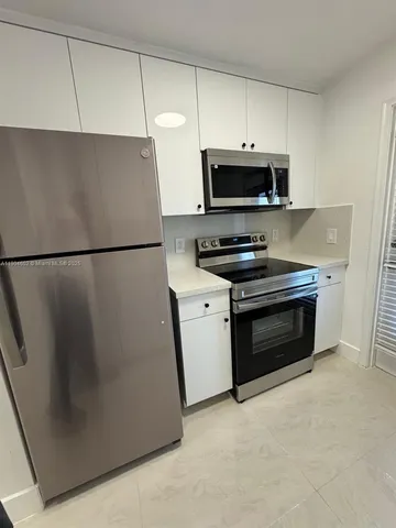 a kitchen with stainless steel appliances a refrigerator stove and white cabinets