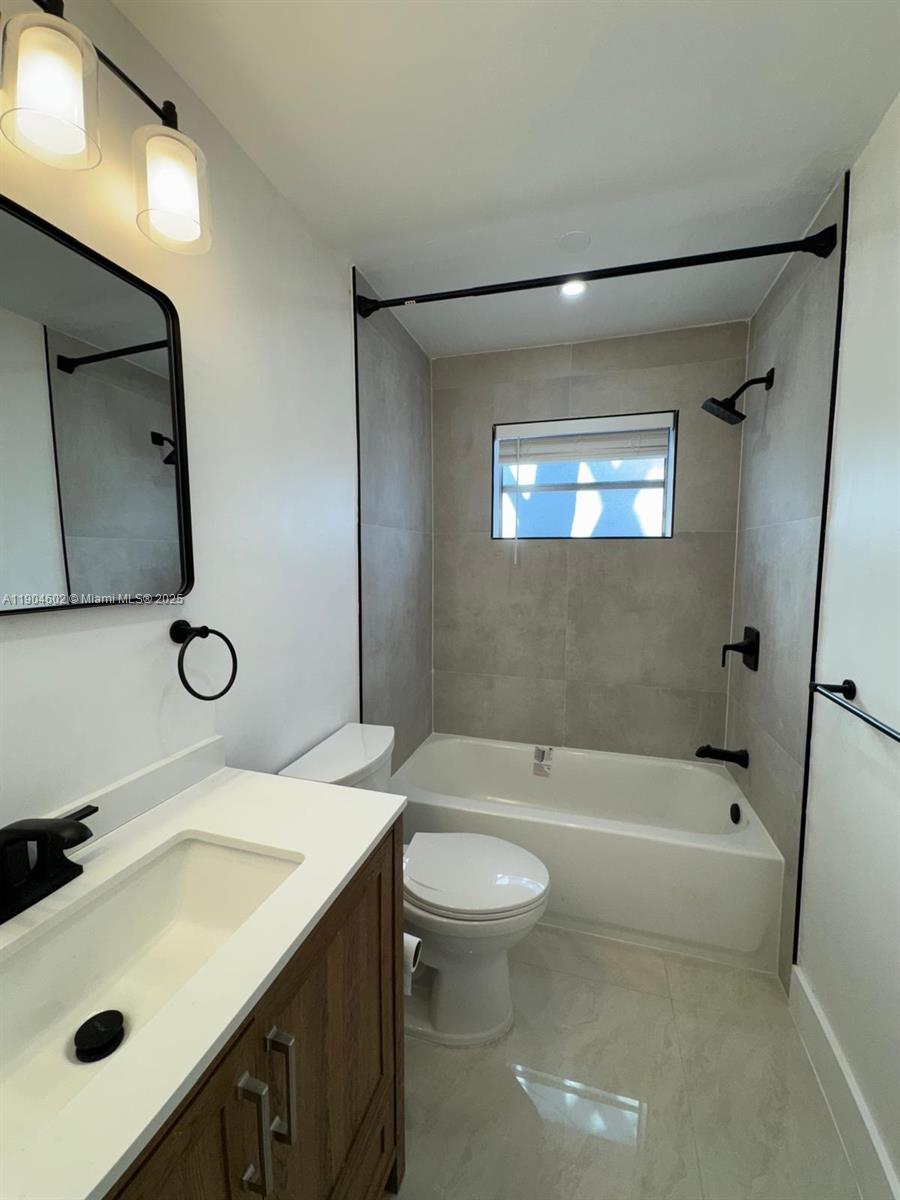 2418 Polk Street, Unit 104 Hollywood, FL 33020 - Photo 6 of 16 a bathroom with a sink a toilet and shower