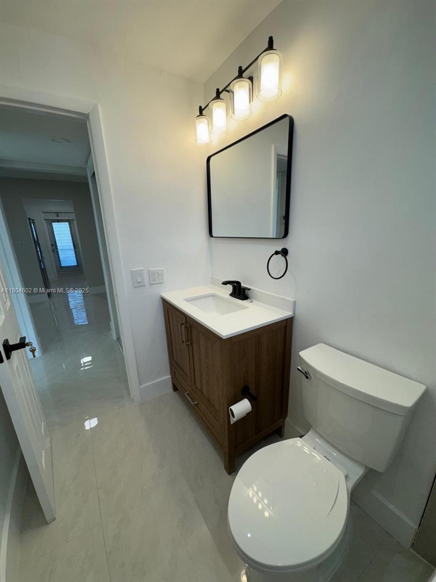 2418 Polk Street, Unit 104 Hollywood, FL 33020 - Photo 7 of 16 a bathroom with a toilet sink and mirror