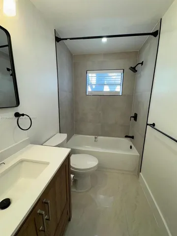 a bathroom with a granite countertop sink a toilet a mirror and shower