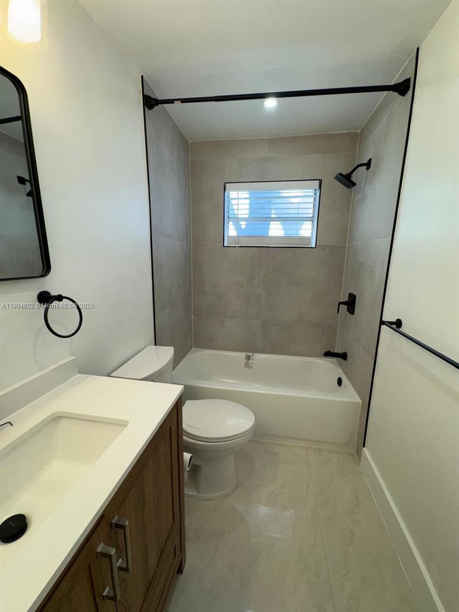 2418 Polk Street, Unit 104 Hollywood, FL 33020 - Photo 8 of 16 a bathroom with a granite countertop sink a toilet a mirror and shower