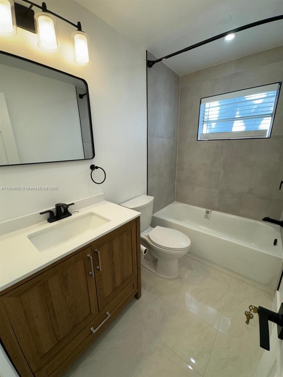 2418 Polk Street, Unit 104 Hollywood, FL 33020 - Photo 9 of 16 a bathroom with a sink a toilet and a bathtub