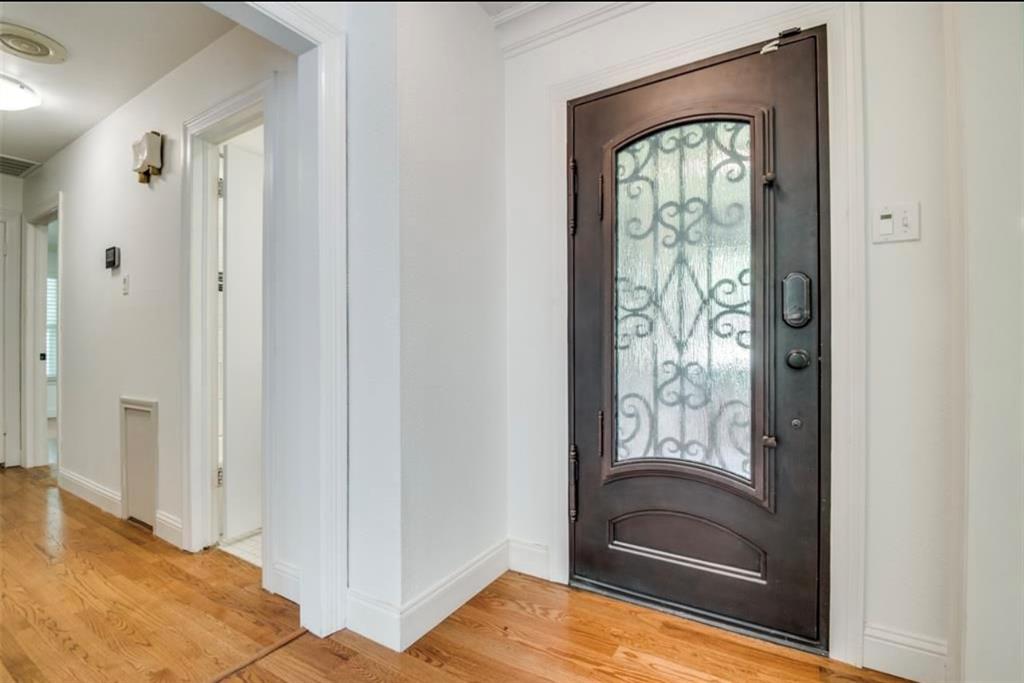 13038 Copenhill Road Dallas, TX 75240 - Photo 2 of 15 Wrought iron entry door with an arched glass insert, wood-finish flooring, and white painted walls