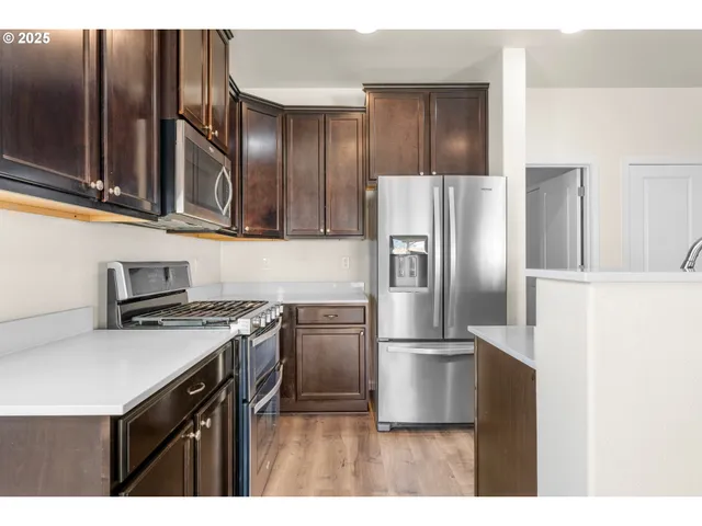 a kitchen with stainless steel appliances granite countertop a refrigerator a stove and a sink