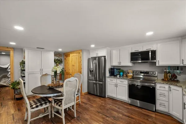 a kitchen with stainless steel appliances a sink dishwasher a stove top oven a refrigerator with wooden floor and cabinets