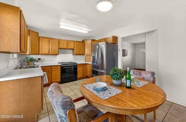 a kitchen with stainless steel appliances granite countertop a table chairs and a refrigerator