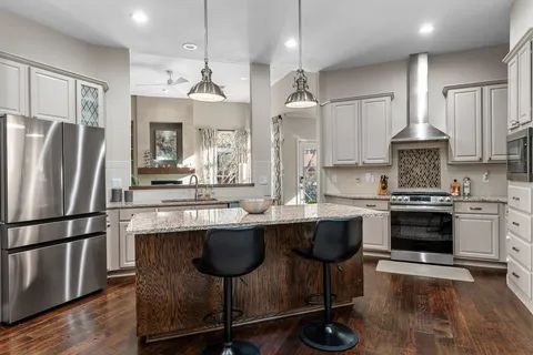 a kitchen with granite countertop kitchen island a sink stove and refrigerator