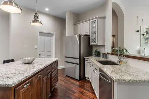 a kitchen with stainless steel appliances granite countertop a sink stove refrigerator and cabinets