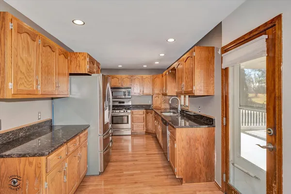 a kitchen with stainless steel appliances granite countertop a stove top oven a sink and a refrigerator