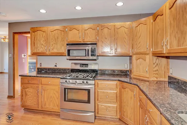 a kitchen with granite countertop a stove top oven microwave and cabinets