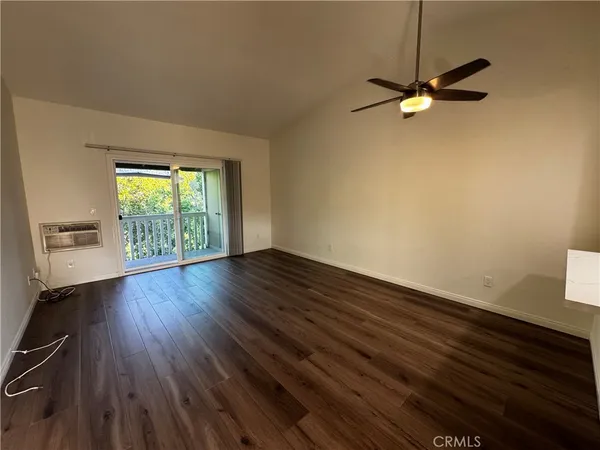 an empty room with wooden floor fan and windows