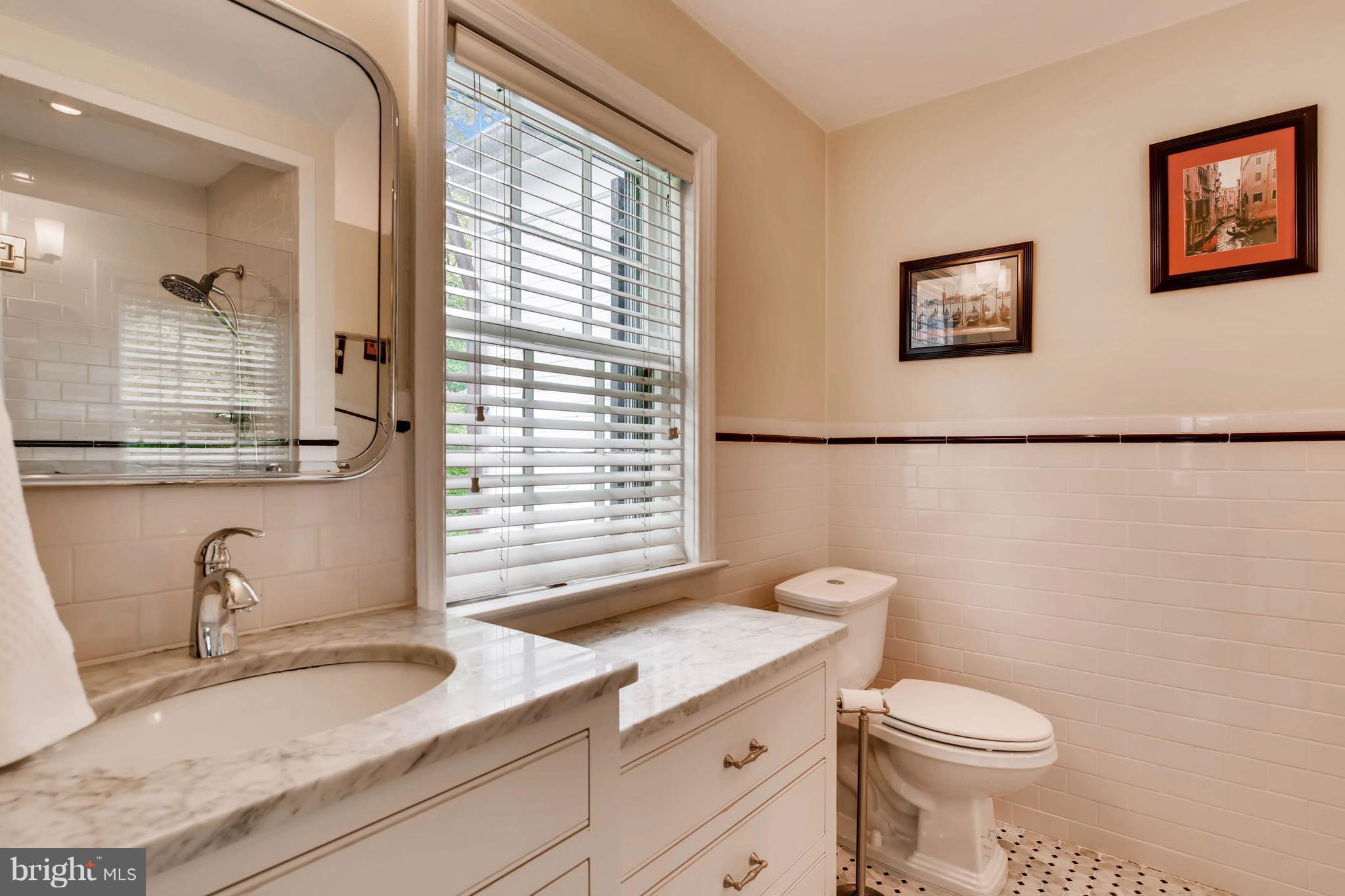 106 Enfield Road Baltimore, MD 21212 - Photo 15 of 27 a bathroom with a granite countertop sink toilet a mirror and a window