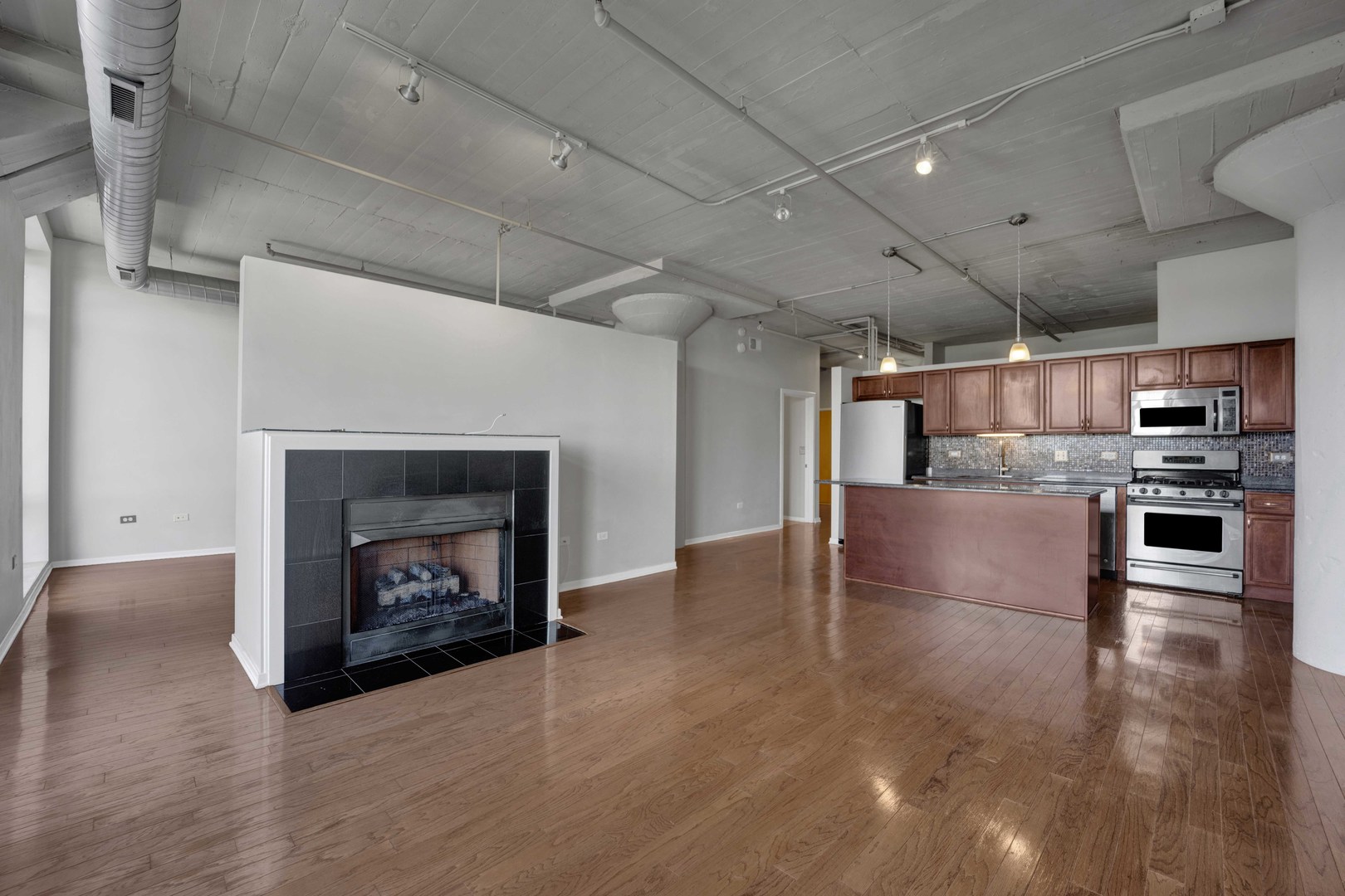 1525 South Sangamon Street, Unit 504 Chicago, IL 60608 - Photo 11 of 32 a open kitchen with stainless steel appliances wooden floor and a fireplace