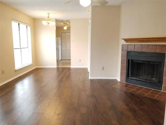 an empty room with wooden floor fireplace and windows