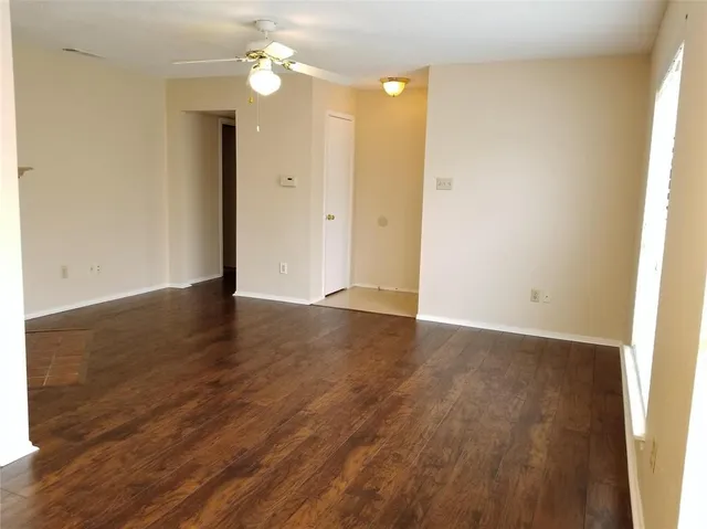 an empty room with wooden floor fan and window