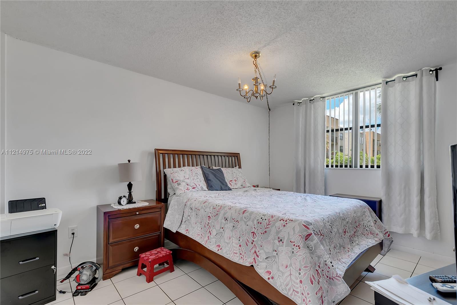 8002 Southwest 149th Avenue, Unit B201 Miami, FL 33193 - Photo 9 of 18 a bedroom with a bed and a dresser in it