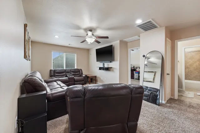 a living room with furniture a ceiling fan and a flat screen tv