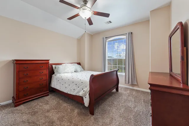 a spacious bedroom with a bed and a dresser