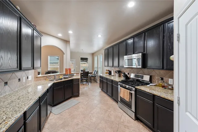 a large kitchen with stainless steel appliances granite countertop a sink stove and refrigerator