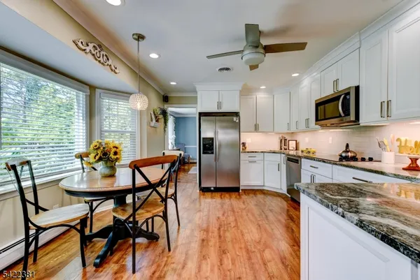 a kitchen with stainless steel appliances granite countertop a stove top oven a sink dishwasher a dining table and chairs with wooden floor