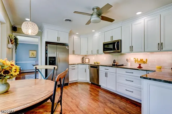 a kitchen with stainless steel appliances granite countertop a stove refrigerator a microwave oven a sink a dining table and chairs with wooden floor