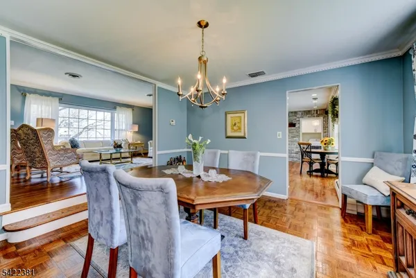 a dining room with wooden floor a chandelier a wooden table and chairs