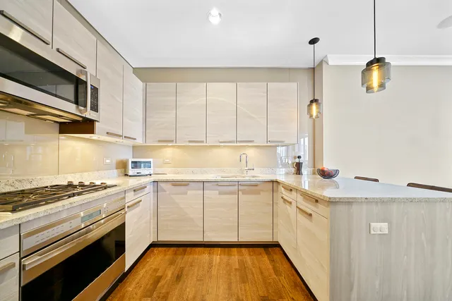 a kitchen with stainless steel appliances a sink dishwasher stove and white cabinets with wooden floor
