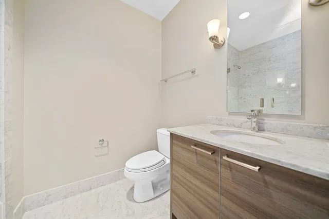 a bathroom with a granite countertop sink a toilet and a mirror