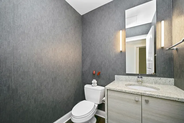 a bathroom with a granite countertop sink toilet and a mirror