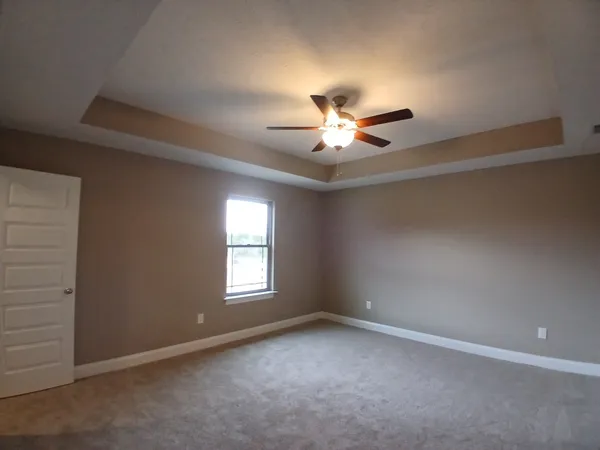 an empty room with windows and fan