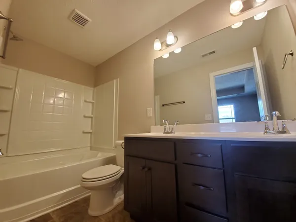 an empty room with wooden floor closet and windows