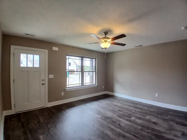 a view of an empty room with wooden floor and a window