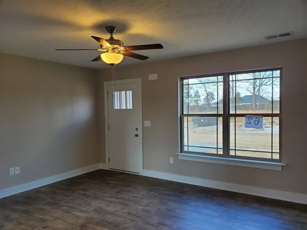 a view of an empty room with wooden floor and a window