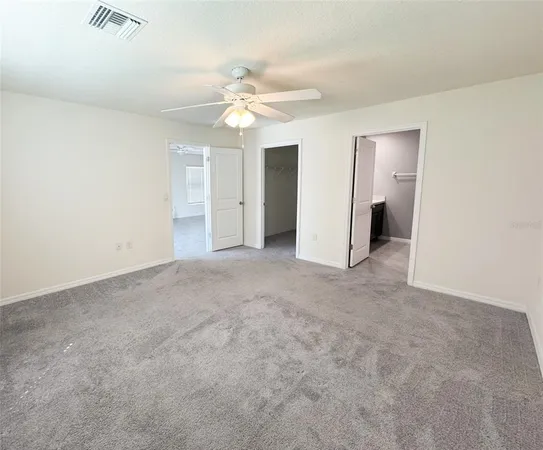 an empty room with a bathroom and a fan