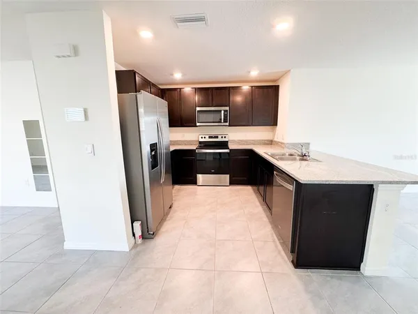 a large kitchen with stainless steel appliances a refrigerator and a sink